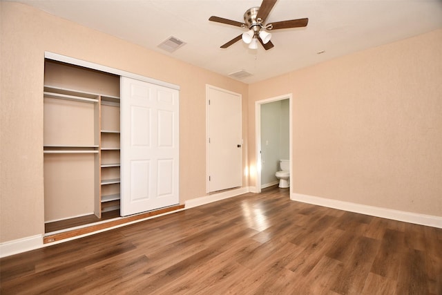 unfurnished bedroom with a closet, dark hardwood / wood-style floors, ensuite bath, and ceiling fan