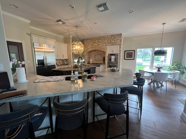 kitchen featuring white cabinets, a kitchen breakfast bar, hanging light fixtures, a large island, and stainless steel appliances