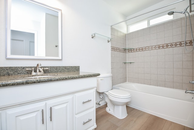 full bathroom with vanity, tiled shower / bath, hardwood / wood-style floors, and toilet