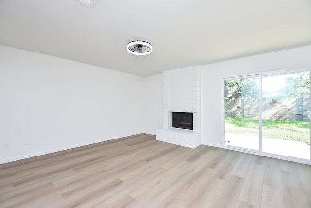 unfurnished living room featuring a brick fireplace and light hardwood / wood-style floors