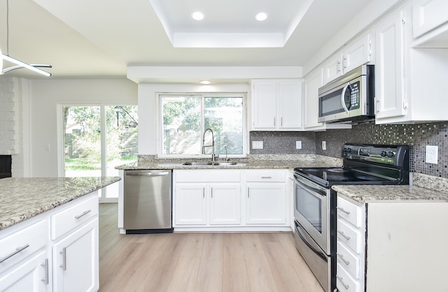 kitchen with white cabinets, appliances with stainless steel finishes, plenty of natural light, and light hardwood / wood-style floors