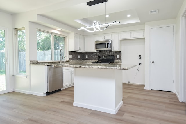 kitchen featuring white cabinetry, a raised ceiling, light stone countertops, pendant lighting, and stainless steel appliances