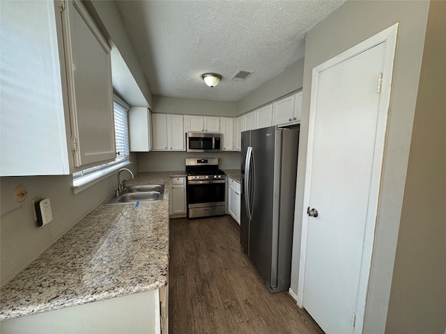 kitchen with white cabinetry, sink, dark wood-type flooring, light stone counters, and appliances with stainless steel finishes