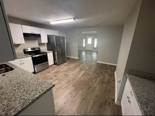 kitchen featuring appliances with stainless steel finishes, light hardwood / wood-style flooring, light stone counters, and white cabinets