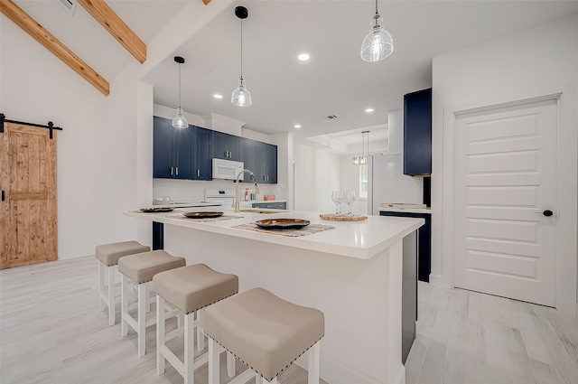 kitchen featuring light wood-type flooring, blue cabinetry, a barn door, a kitchen bar, and decorative light fixtures