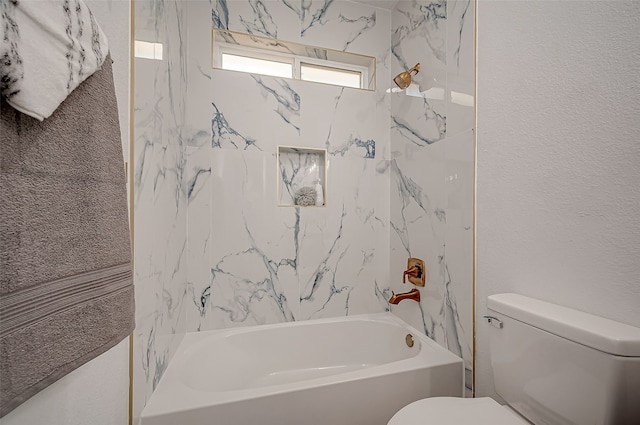 bathroom featuring tiled shower / bath combo and toilet