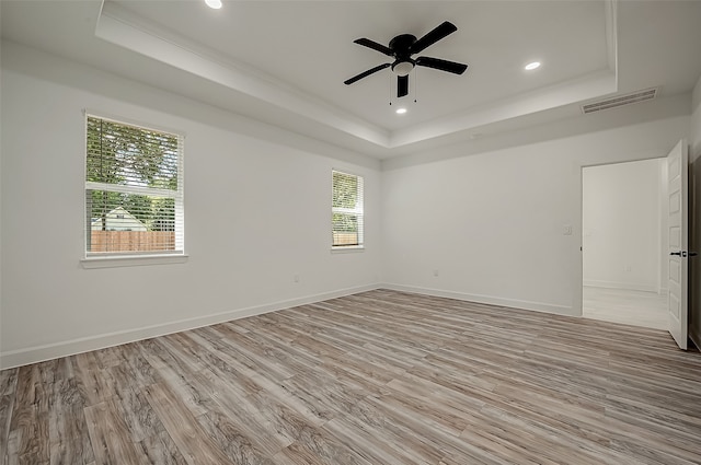 spare room with a tray ceiling, light hardwood / wood-style flooring, and ceiling fan