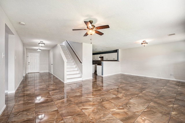 unfurnished living room with ceiling fan and a textured ceiling