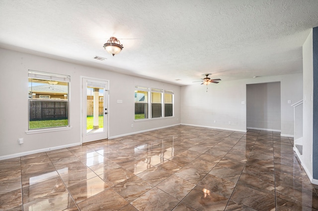 unfurnished room with ceiling fan and a textured ceiling