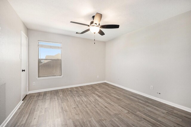 empty room with a textured ceiling, dark hardwood / wood-style flooring, and ceiling fan