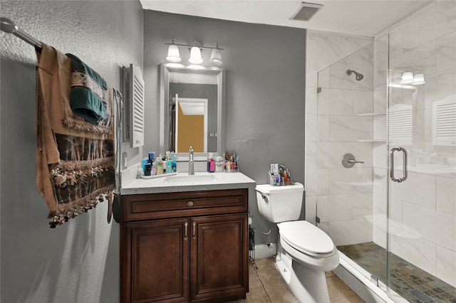 bathroom featuring tile patterned flooring, vanity, toilet, and a shower with door