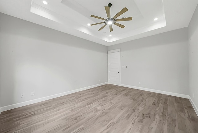 spare room featuring a tray ceiling, light hardwood / wood-style floors, and ceiling fan