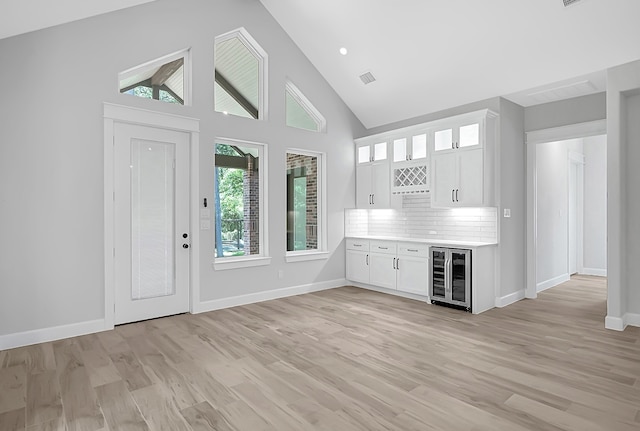 interior space with light hardwood / wood-style floors, wine cooler, white cabinets, and tasteful backsplash