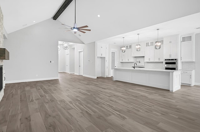 unfurnished living room featuring beam ceiling, ceiling fan, high vaulted ceiling, and dark hardwood / wood-style flooring