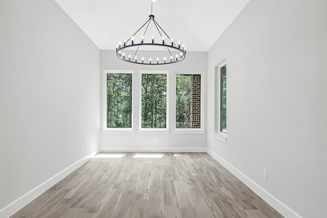 unfurnished dining area featuring lofted ceiling, a chandelier, and light wood-type flooring