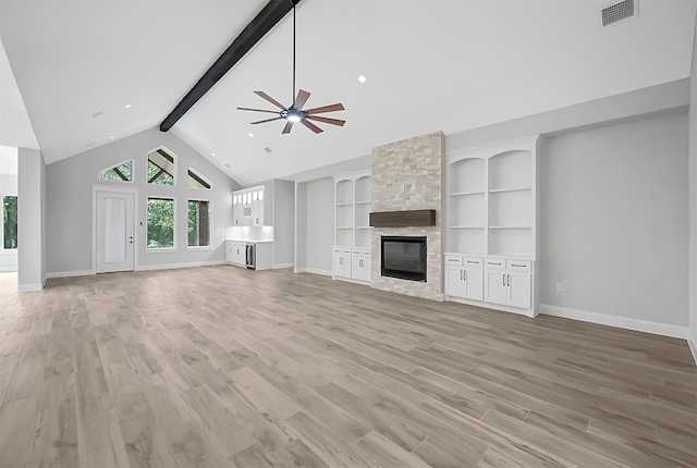 unfurnished living room featuring beam ceiling, light hardwood / wood-style flooring, a fireplace, and ceiling fan