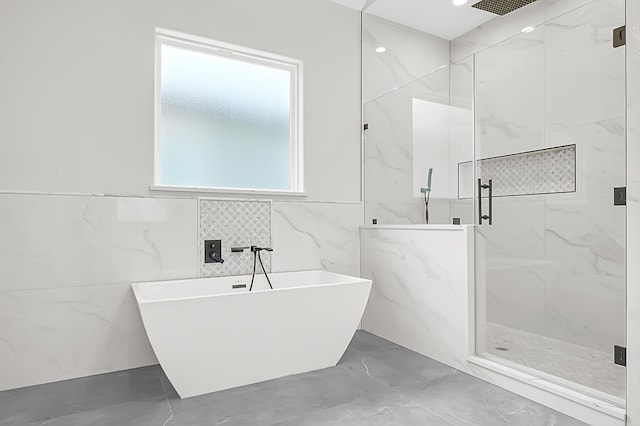 bathroom featuring plus walk in shower and tile walls