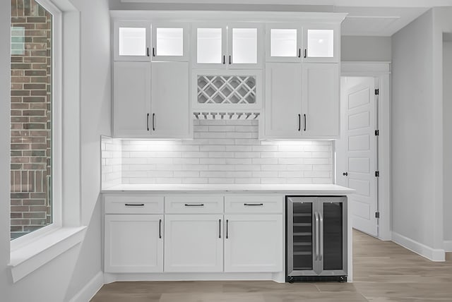 bar featuring light hardwood / wood-style floors, wine cooler, white cabinets, and backsplash