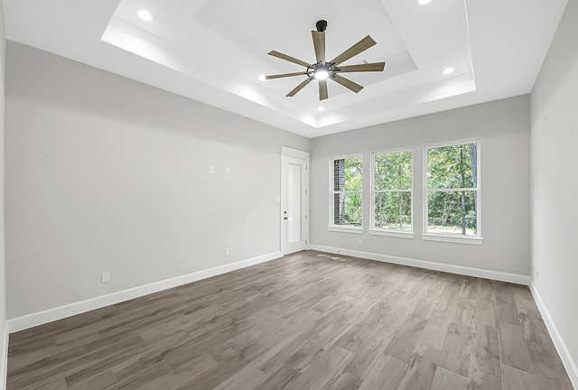 spare room with ceiling fan, wood-type flooring, and a raised ceiling