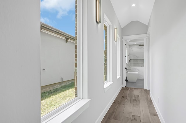 corridor with vaulted ceiling and light wood-type flooring