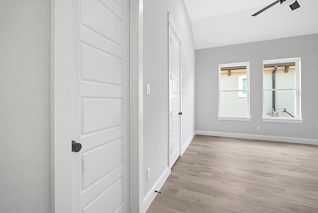 corridor featuring vaulted ceiling and light hardwood / wood-style floors