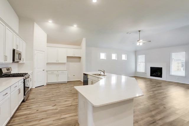 kitchen featuring light hardwood / wood-style floors, white cabinetry, stainless steel appliances, ceiling fan, and a kitchen island with sink