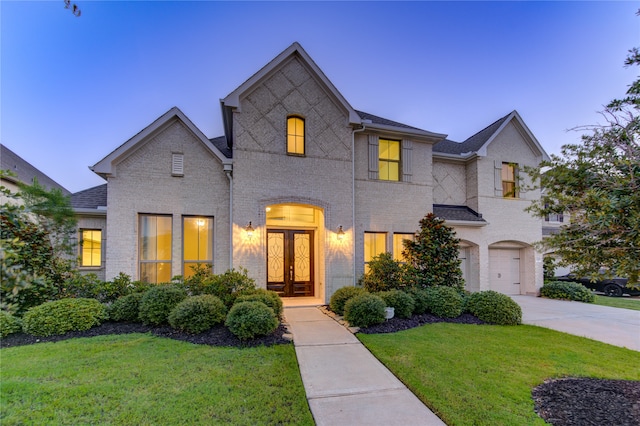 french country inspired facade with a lawn, a garage, and french doors