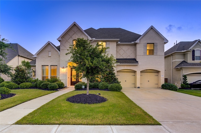 french provincial home featuring a garage and a front lawn