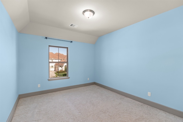 empty room with vaulted ceiling and light colored carpet