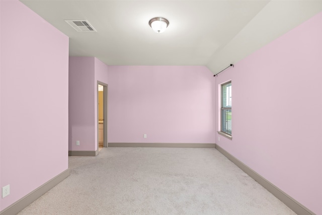 carpeted empty room featuring vaulted ceiling