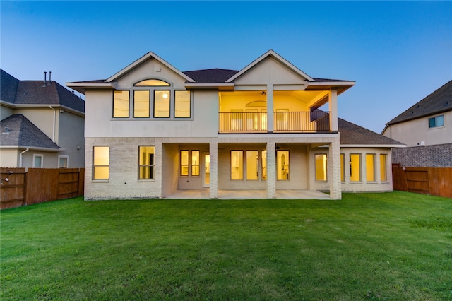 rear view of property with a balcony, a patio, and a yard