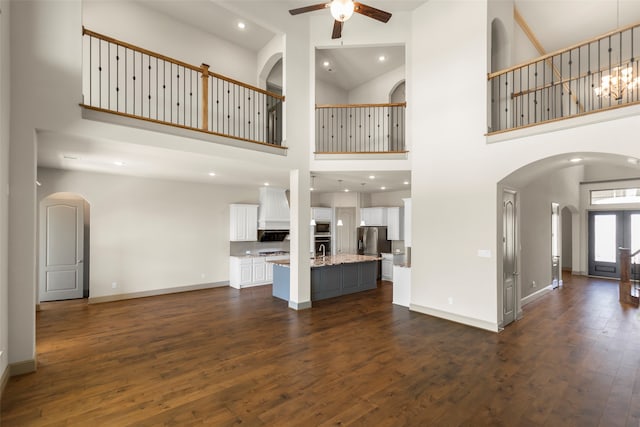 unfurnished living room featuring dark hardwood / wood-style floors, ceiling fan, sink, and high vaulted ceiling