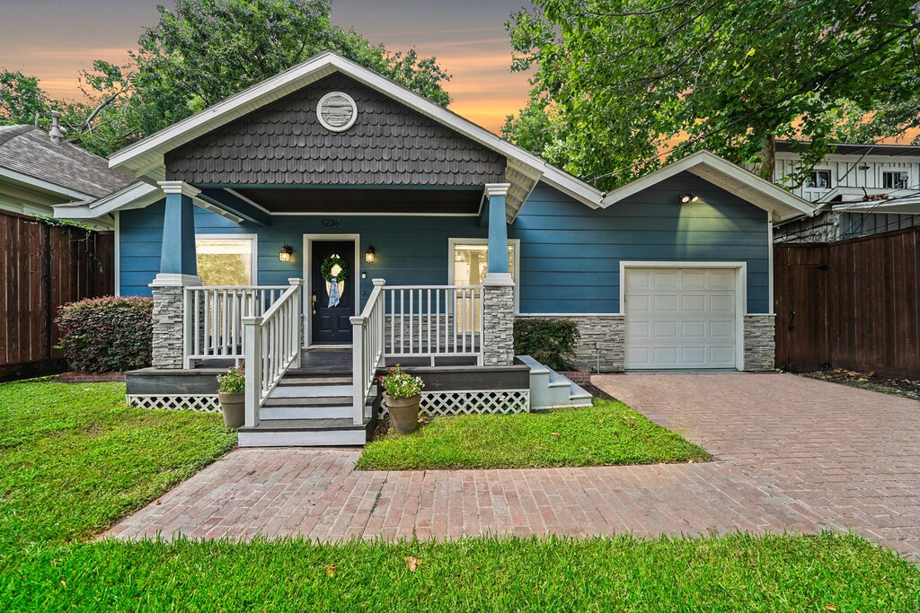 bungalow-style home with a lawn, a porch, and a garage