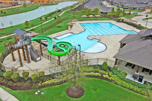 view of swimming pool featuring a lawn, a water view, and a playground