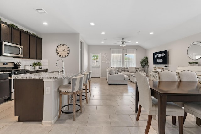 kitchen with dark brown cabinets, sink, appliances with stainless steel finishes, and an island with sink