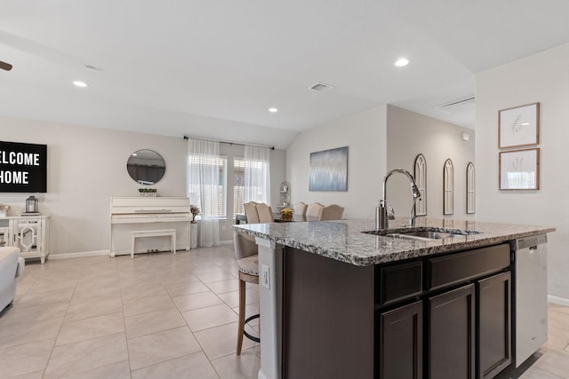 kitchen featuring stone counters, dishwasher, sink, a center island with sink, and light tile patterned flooring