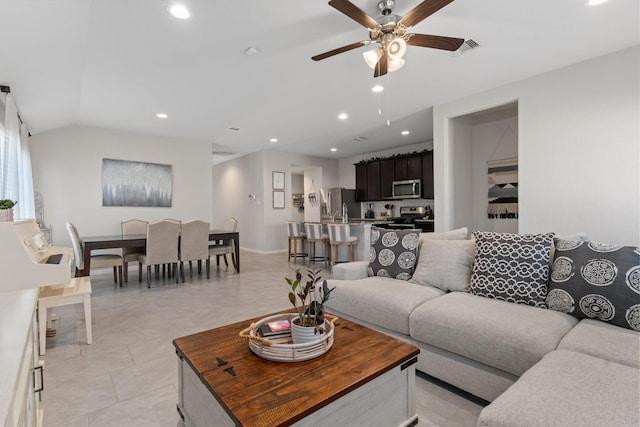 living room featuring ceiling fan, light tile patterned floors, and vaulted ceiling