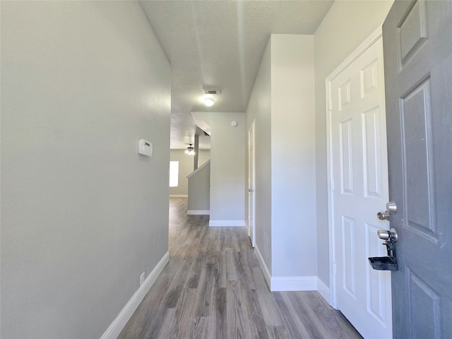 hall with wood-type flooring and a textured ceiling