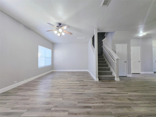 unfurnished living room featuring ceiling fan, hardwood / wood-style floors, and a textured ceiling