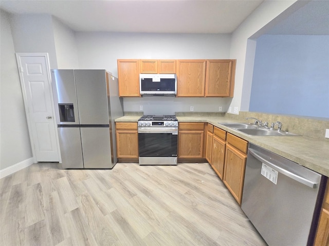 kitchen with light hardwood / wood-style floors, sink, kitchen peninsula, and stainless steel appliances