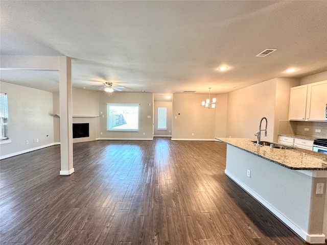 unfurnished living room with dark hardwood / wood-style flooring, a textured ceiling, ceiling fan with notable chandelier, and sink