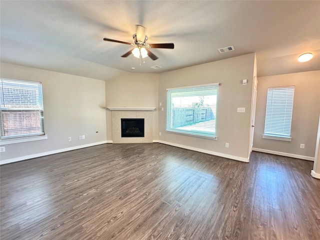 unfurnished living room with a tiled fireplace, ceiling fan, vaulted ceiling, and dark hardwood / wood-style floors