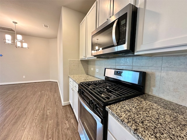 kitchen featuring white cabinets, light stone counters, appliances with stainless steel finishes, and hardwood / wood-style flooring