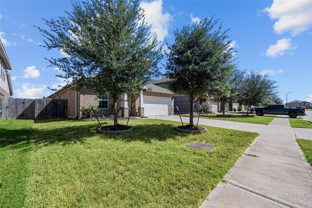 view of property hidden behind natural elements featuring a front lawn and a garage