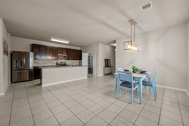 kitchen featuring dark brown cabinets, pendant lighting, appliances with stainless steel finishes, tasteful backsplash, and light tile patterned floors