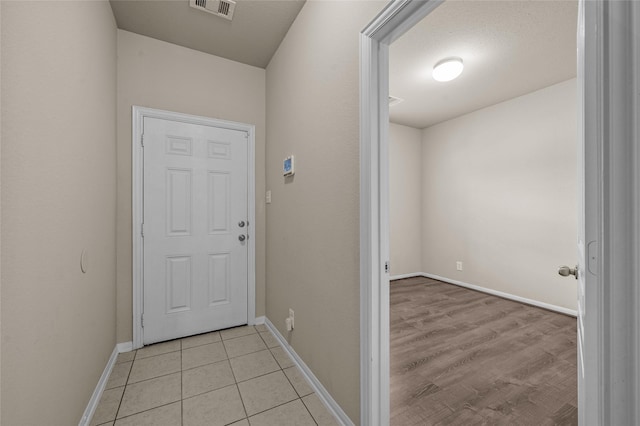 doorway to outside with a textured ceiling and light tile patterned floors