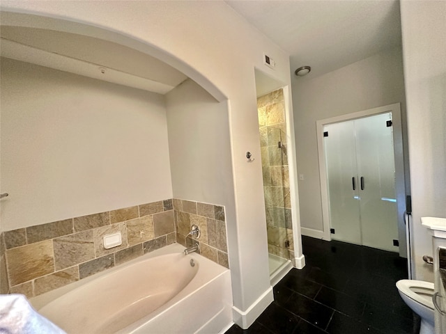 bathroom featuring tile patterned floors, toilet, and shower with separate bathtub