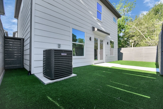 rear view of property featuring a yard and central AC unit