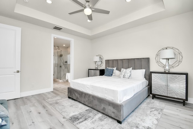 bedroom with a raised ceiling, ceiling fan, and light wood-type flooring