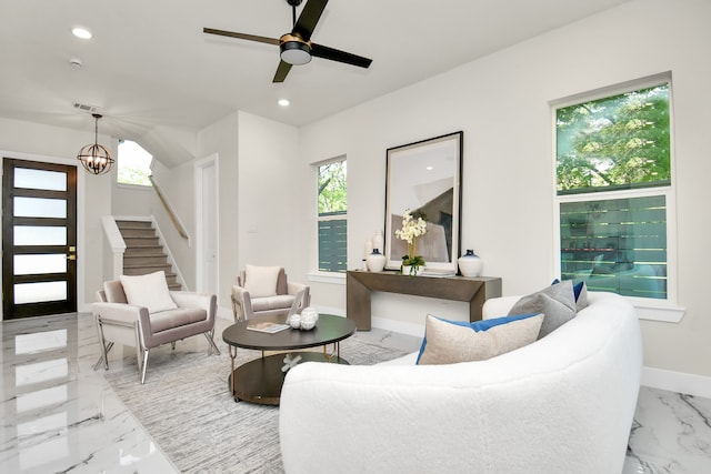 living room featuring ceiling fan with notable chandelier